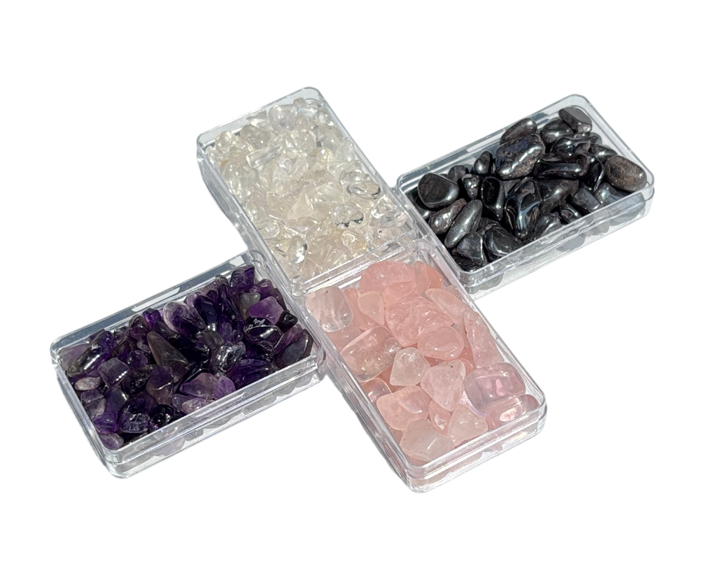 Ansicht von vorn: 4er-Set Amethyst, Bergrkistall, Rosenquarz und Hämatit Trommelsteine in einer Edelsteindose auf weißem Hintergrund