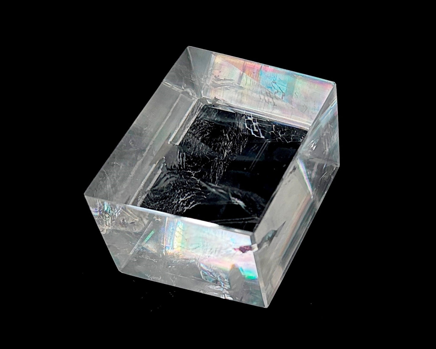 Einzelner polierter Calcit Kristall mit Lichtbrechung auf schwarzem Hintergrund