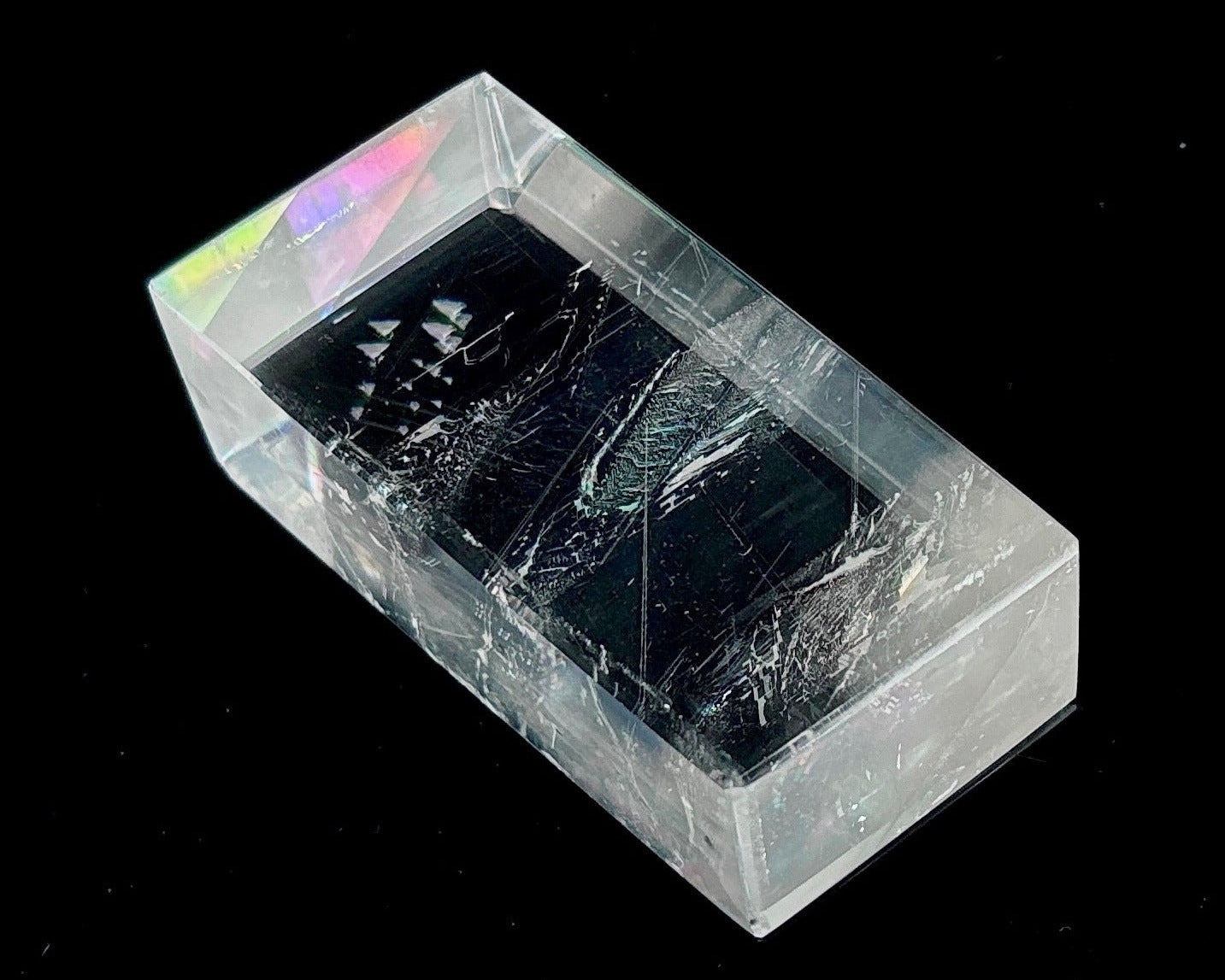 Einzelner polierter Calcit Kristall mit Lichtbrechung auf schwarzem Hintergrund