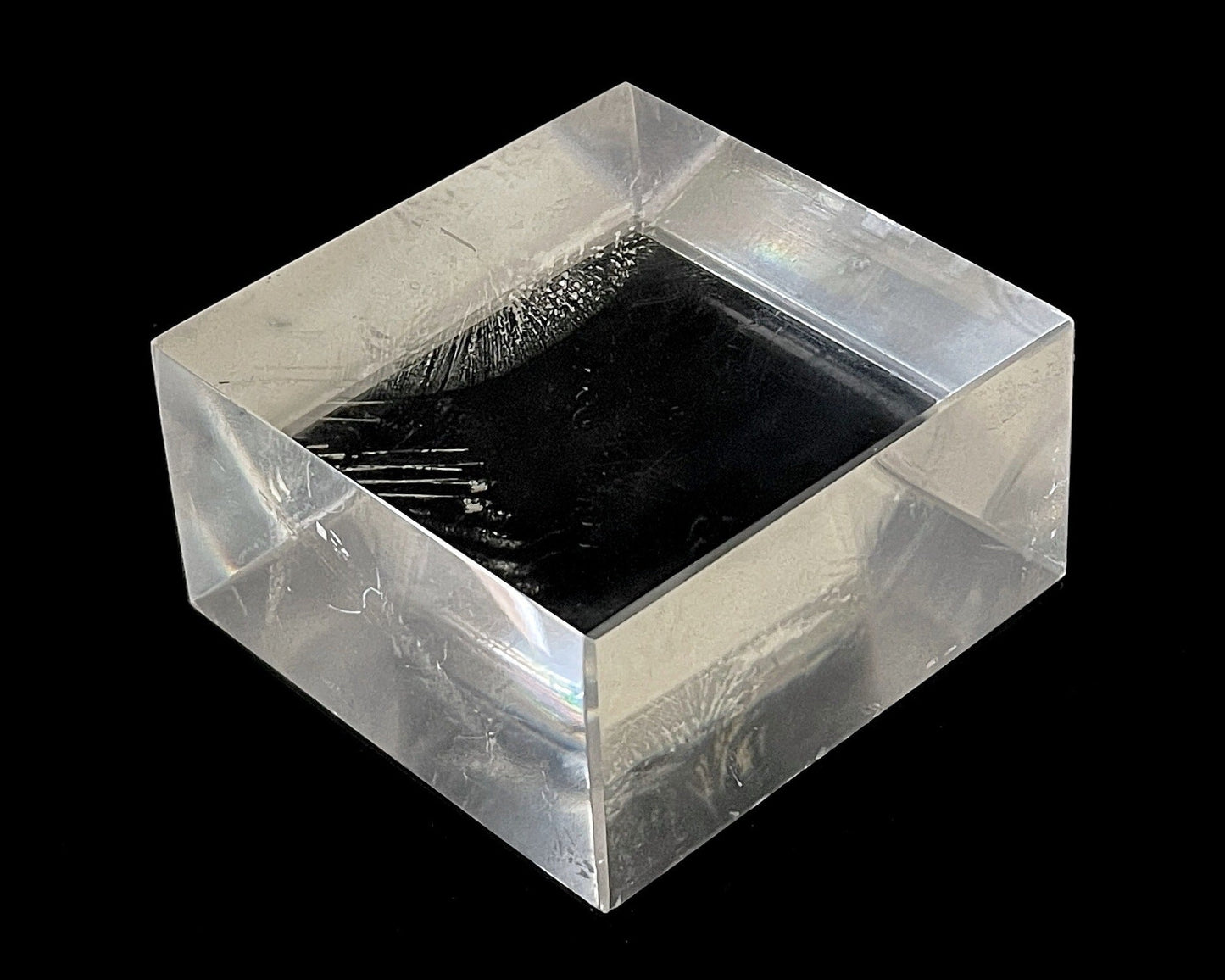 Einzelner polierter Calcit Kristall mit Lichtbrechung auf schwarzem Hintergrund