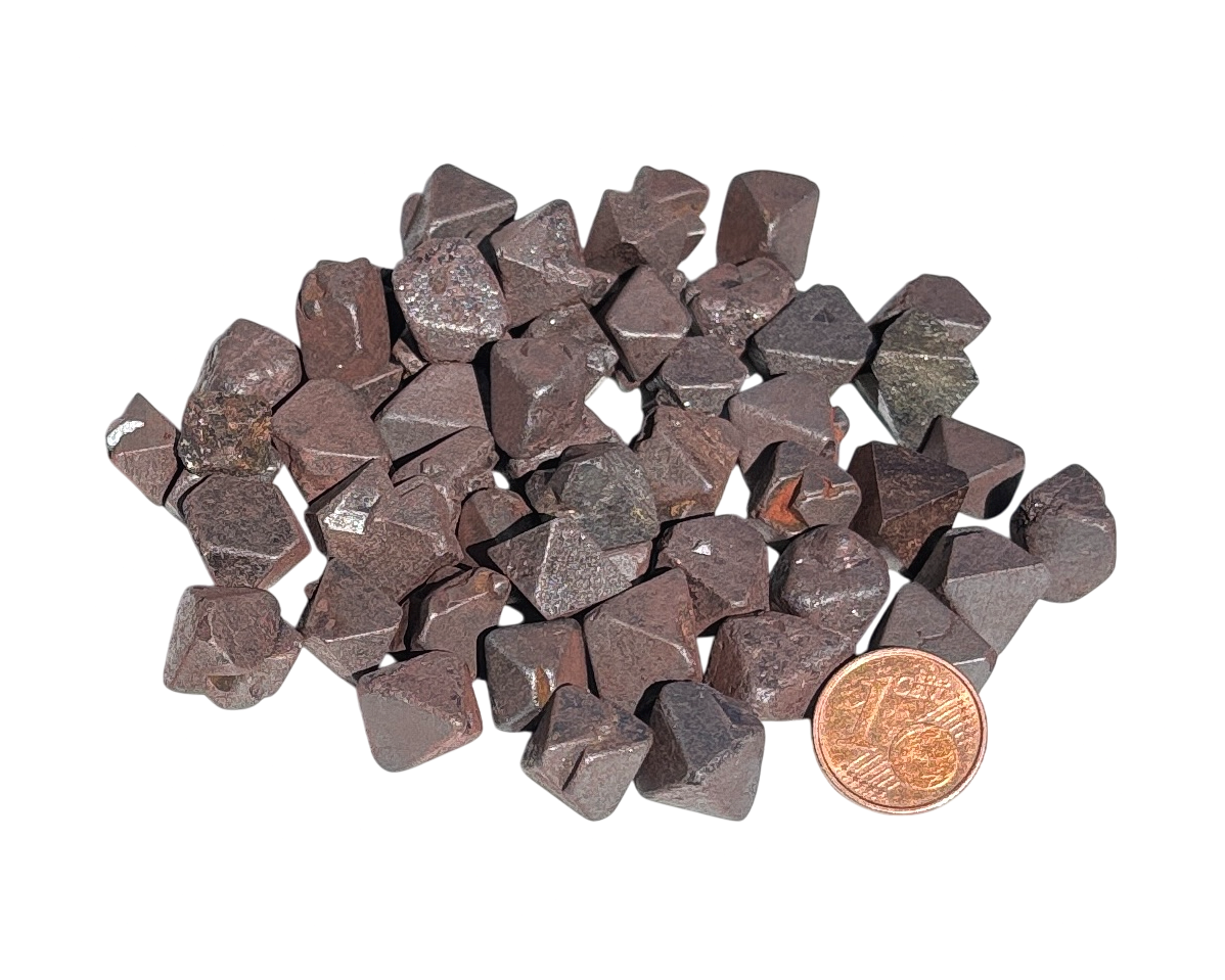 Vielzahl an Magnetit Oktaedern auf weißem Hintergrund im Größenvergleich mit einem Pfennig