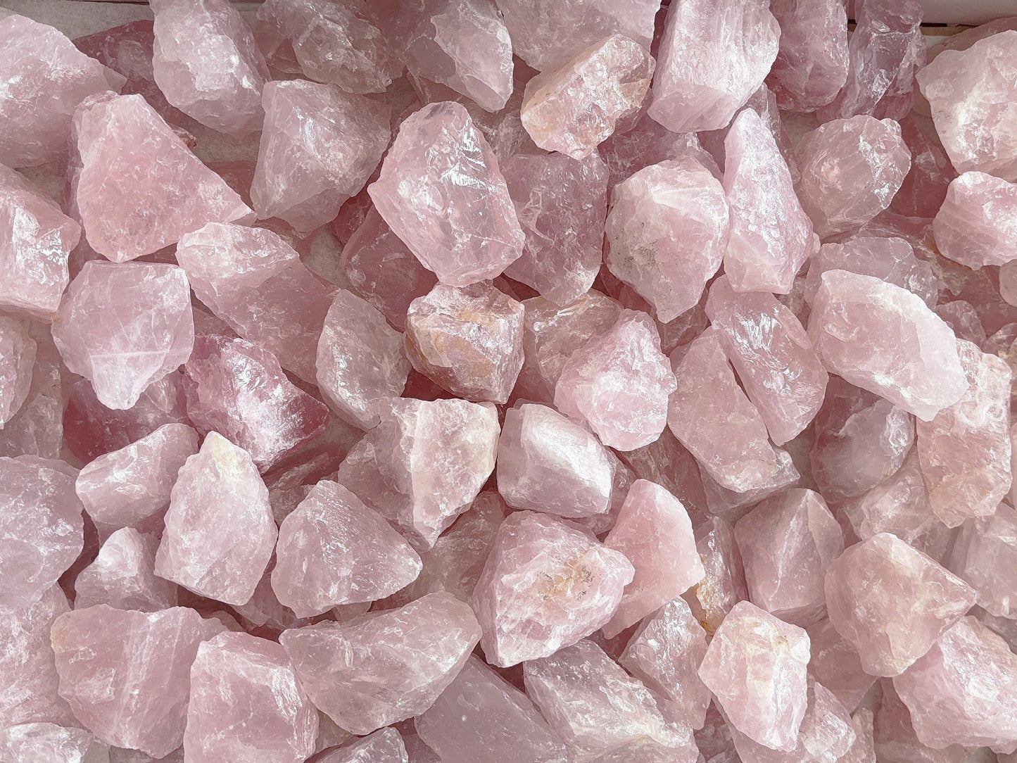 Ansicht von oben: rosefarbene Rosenquarz Rohsteine auf weißem Hintergrund