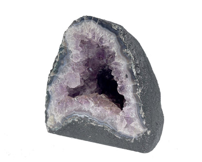 Seitenansicht: einzelne Amethyst Druse mit violetten Kristallen auf weißem Hintergrund