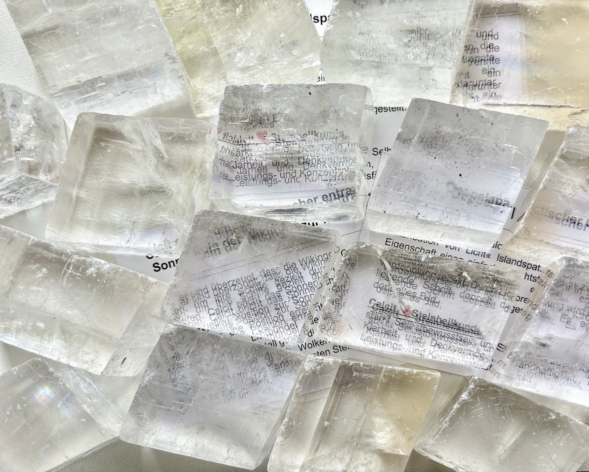 Ansicht von oben: Viele Calcit Kristalle (Doppelspat), die Schrift erscheint doppelt und verschoben auf dem Papier