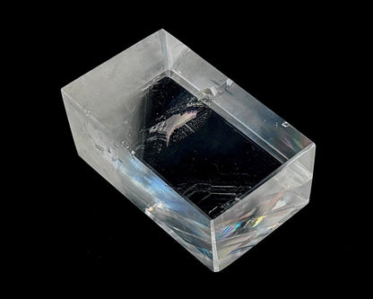 Einzelner polierter Calcit Kristall mit Lichtbrechung auf schwarzem Hintergrund