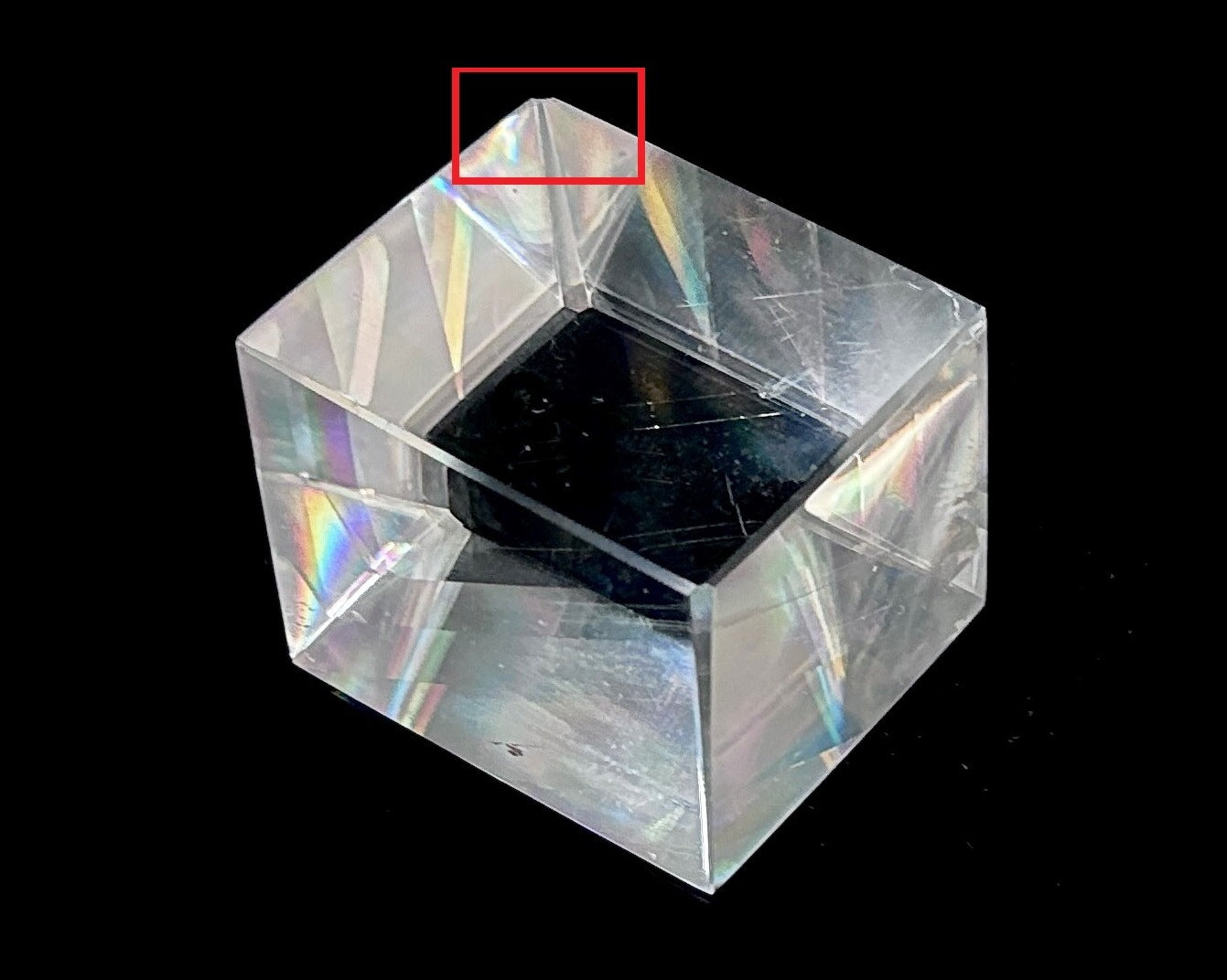 Einzelner polierter Calcit Kristall mit Bestoßung rot eingezeichnet auf schwarzem Hintergrund