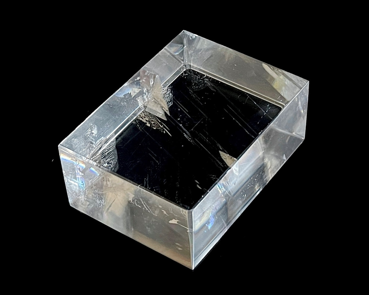 Einzelner polierter Calcit Kristall mit Lichtbrechung auf schwarzem Hintergrund