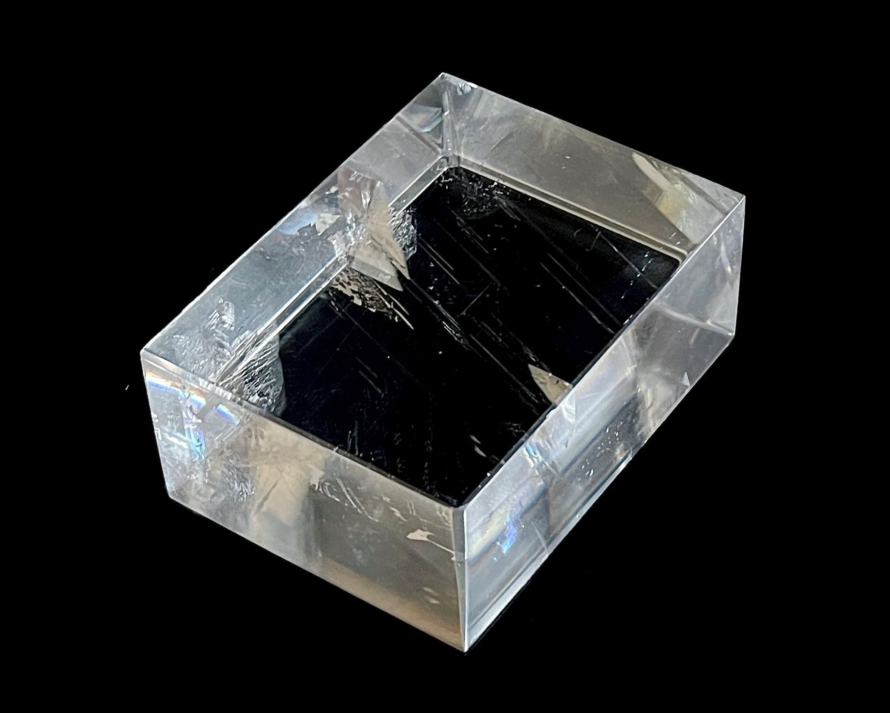 Einzelner polierter Calcit Kristall mit Lichtbrechung auf schwarzem Hintergrund