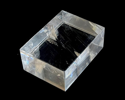 Einzelner polierter Calcit Kristall mit Lichtbrechung auf schwarzem Hintergrund