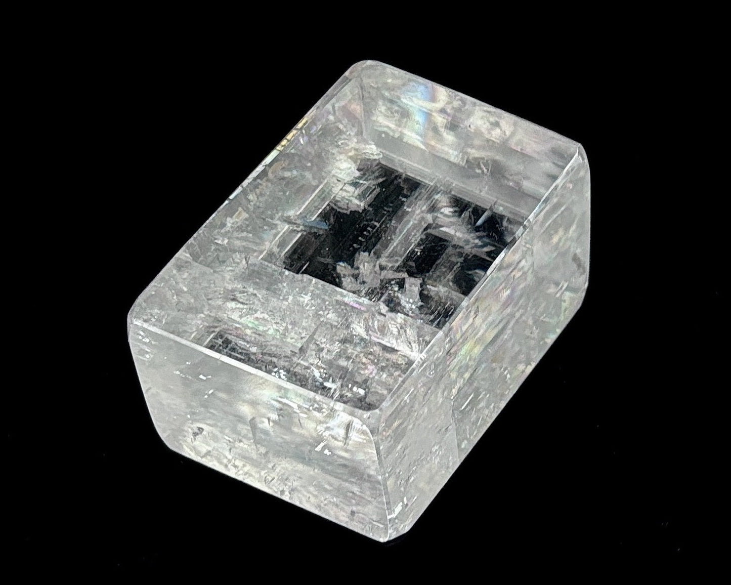 Einzelner polierter Calcit Kristall mit Lichtbrechung auf schwarzem Hintergrund