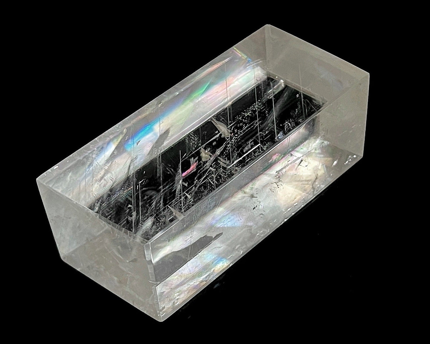 Einzelner polierter Calcit Kristall mit Lichtbrechung auf schwarzem Hintergrund