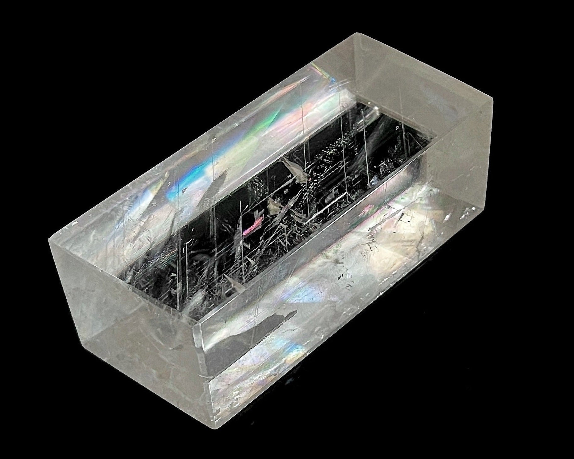 Einzelner polierter Calcit Kristall mit Lichtbrechung auf schwarzem Hintergrund