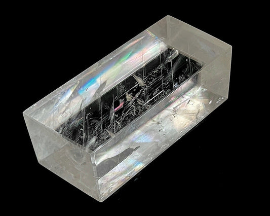 Einzelner polierter Calcit Kristall mit Lichtbrechung auf schwarzem Hintergrund