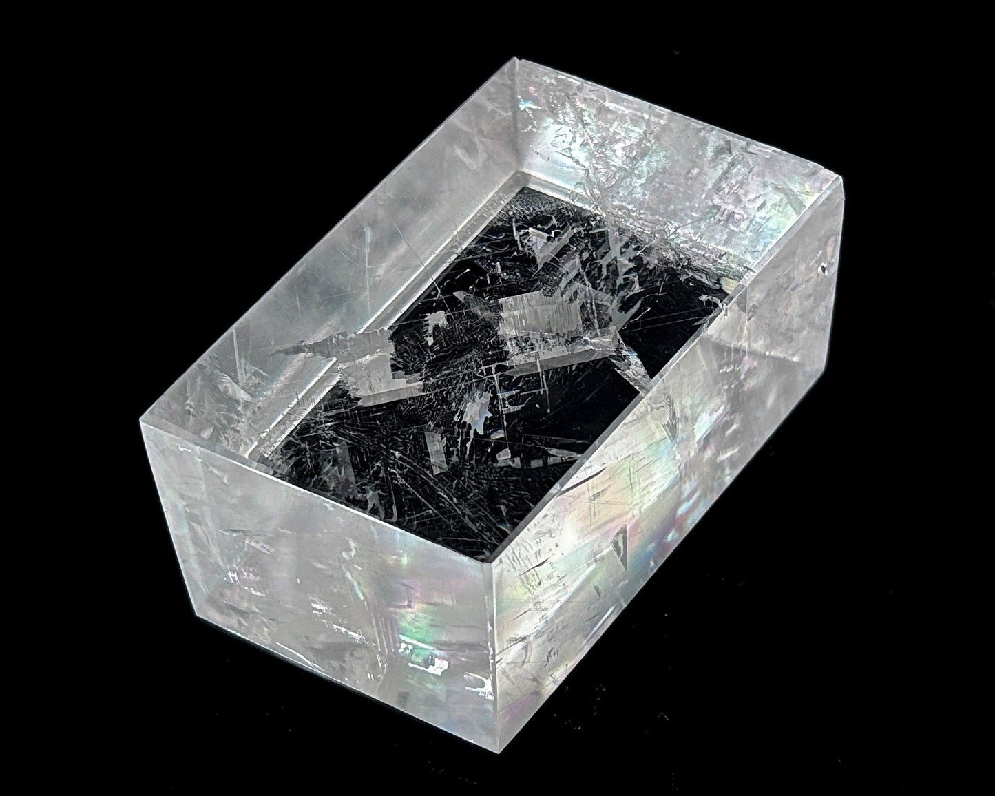 Einzelner polierter Calcit Kristall mit Lichtbrechung auf schwarzem Hintergrund