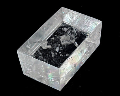 Einzelner polierter Calcit Kristall mit Lichtbrechung auf schwarzem Hintergrund