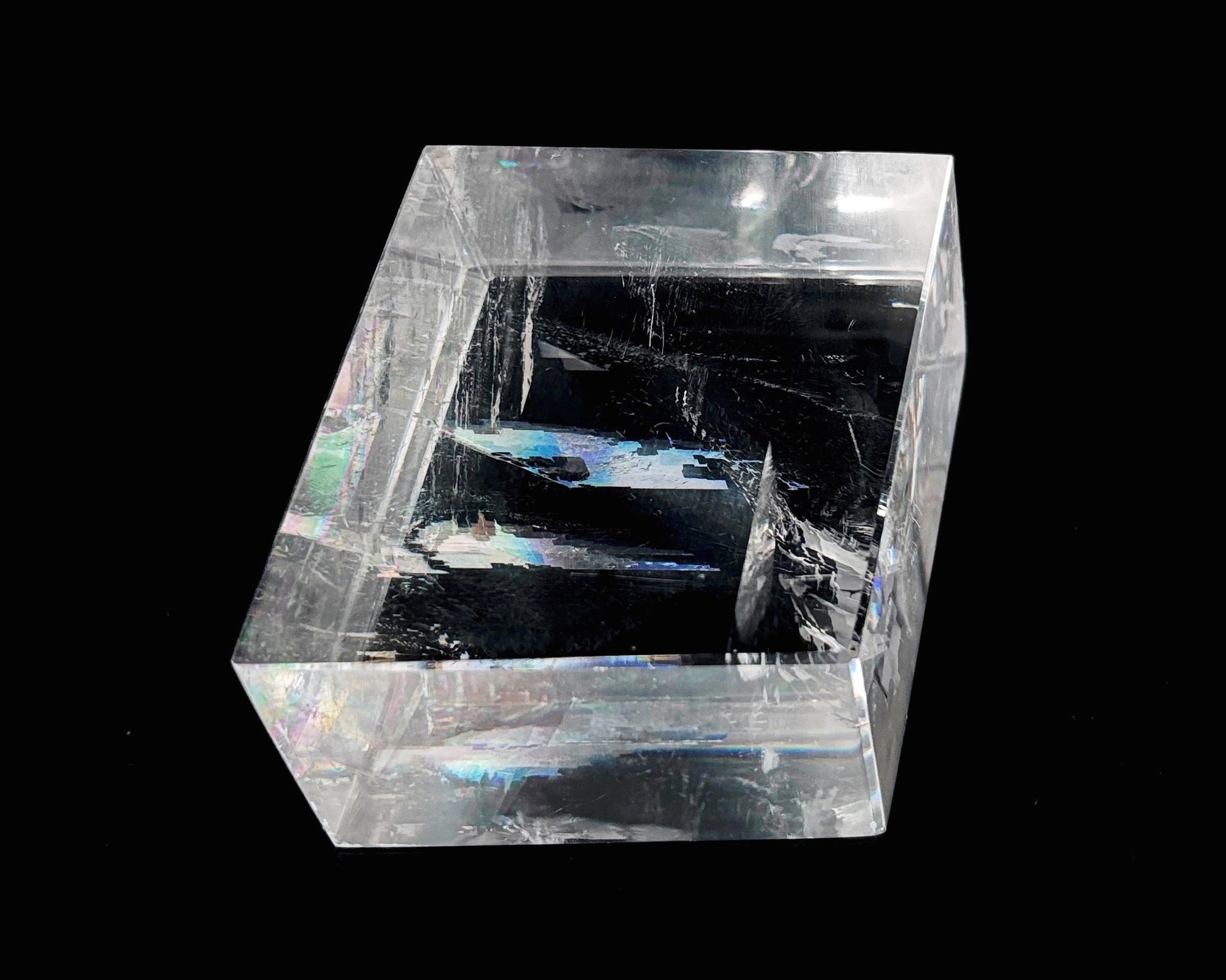 Einzelner polierter Calcit Kristall mit Lichtbrechung auf schwarzem Hintergrund