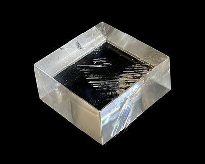 Einzelner polierter Calcit Kristall mit Lichtbrechung auf schwarzem Hintergrund