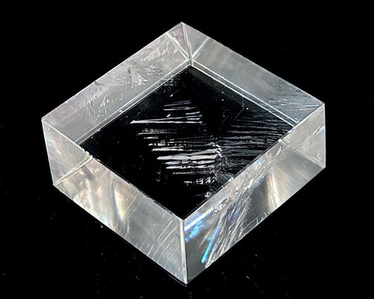 Einzelner polierter Calcit Kristall mit Lichtbrechung auf schwarzem Hintergrund