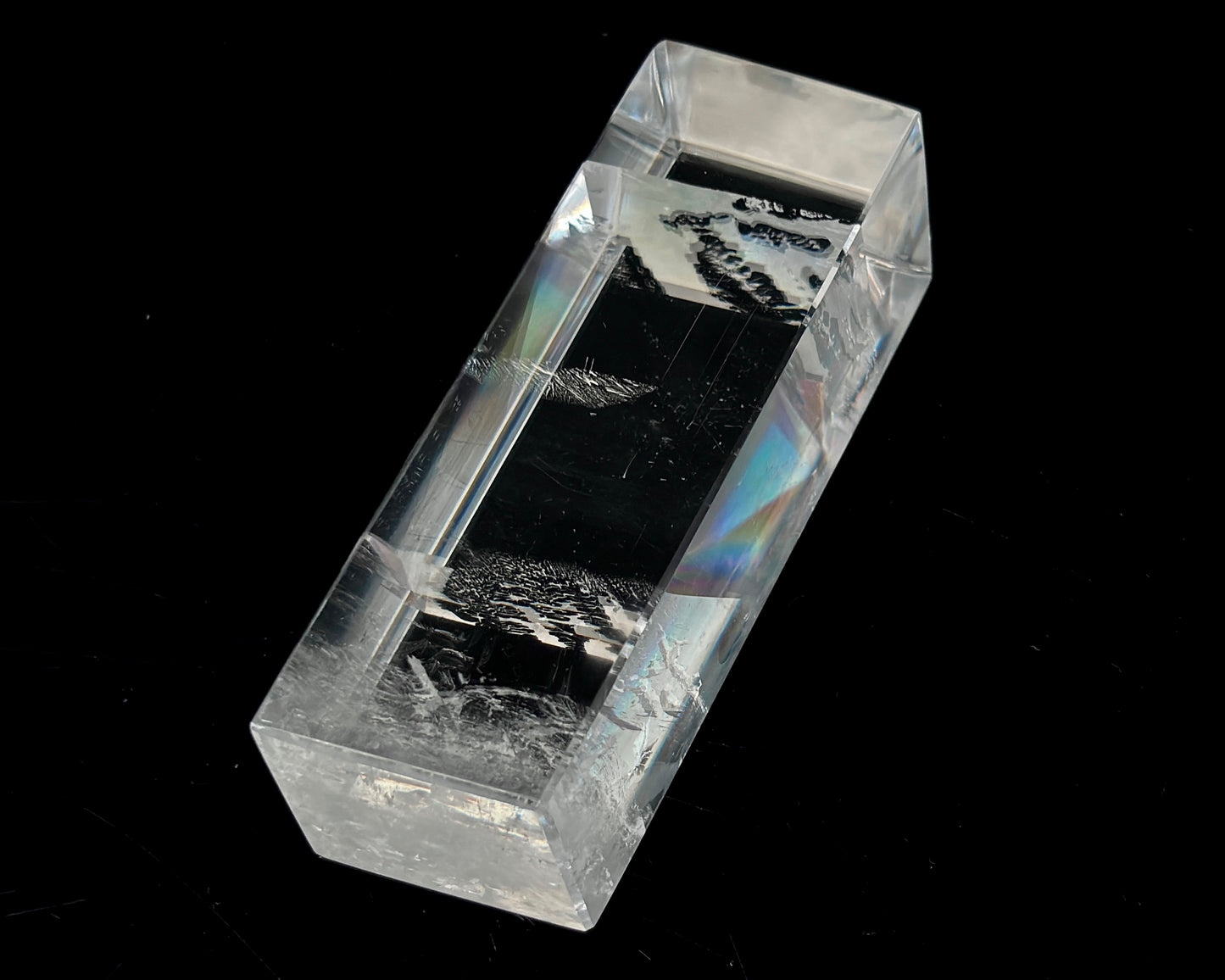 Einzelner polierter Calcit Kristall mit Lichtbrechung auf schwarzem Hintergrund