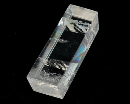 Einzelner polierter Calcit Kristall mit Lichtbrechung auf schwarzem Hintergrund