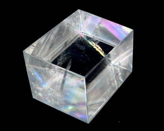 Einzelner polierter Calcit Kristall mit Lichtbrechung auf schwarzem Hintergrund