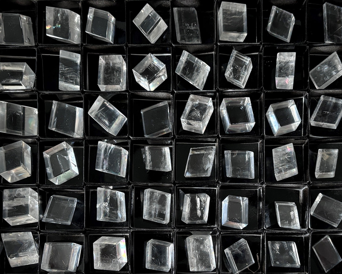 Sammlung polierter kristallklarer Calcit Kristalle (Doppelspat) auf schwarzem Hintergrund