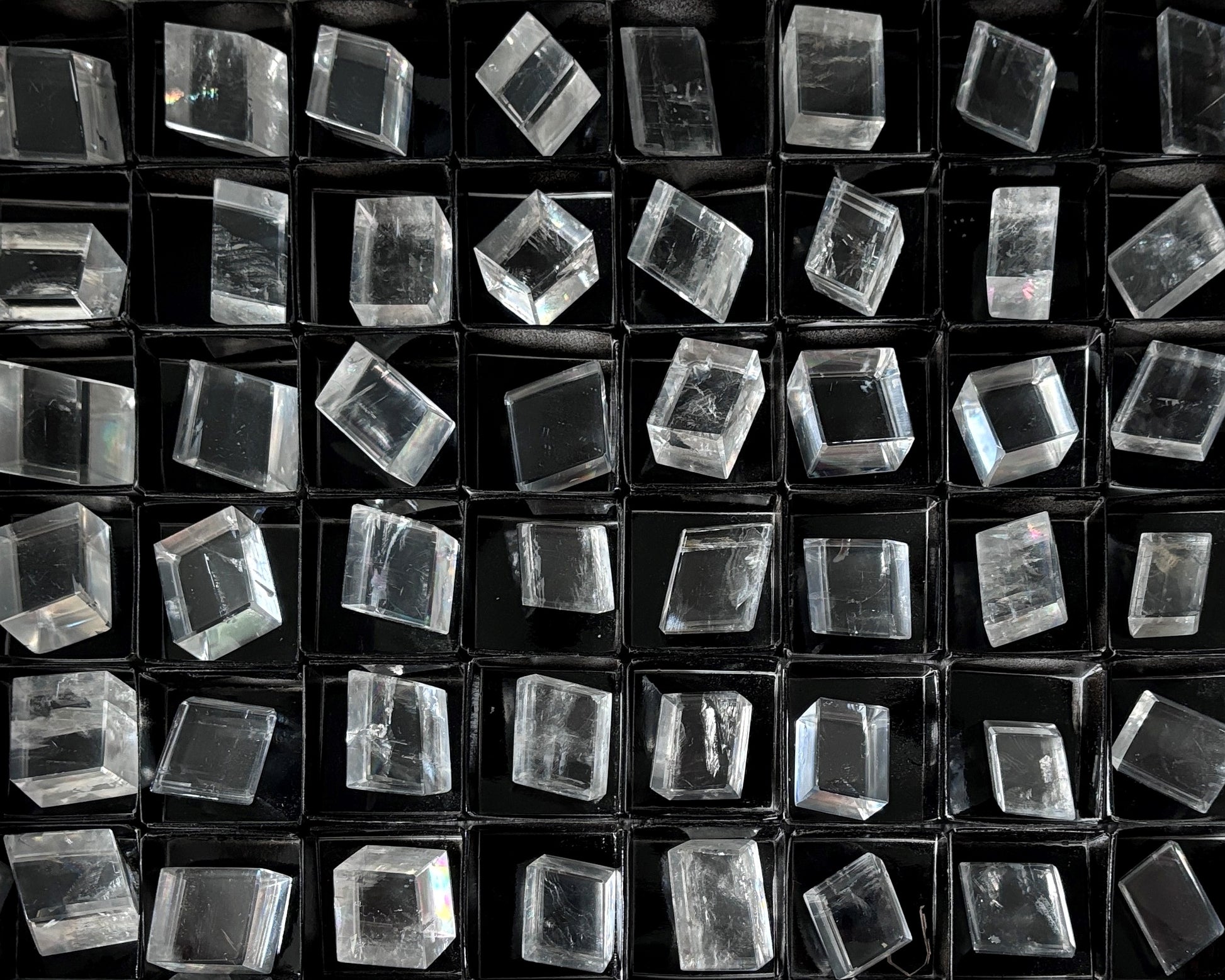 Sammlung polierter kristallklarer Calcit Kristalle (Doppelspat) auf schwarzem Hintergrund