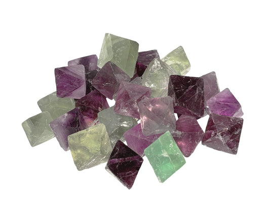 Vielzahl von Fluorit Oktaedern in violett und grün auf weißem Hintergrund