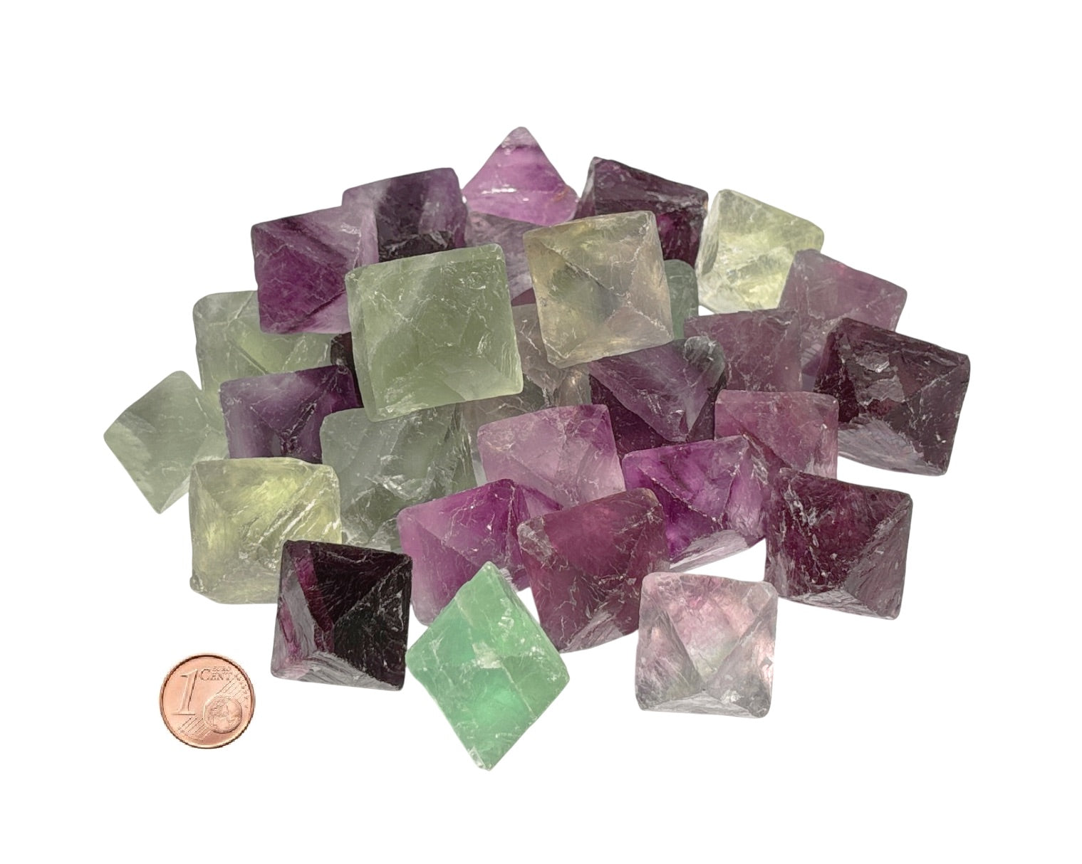 Vielzahl von Fluorit Oktaedern in violett und grün im Größenvergleich mit einem Pfennig