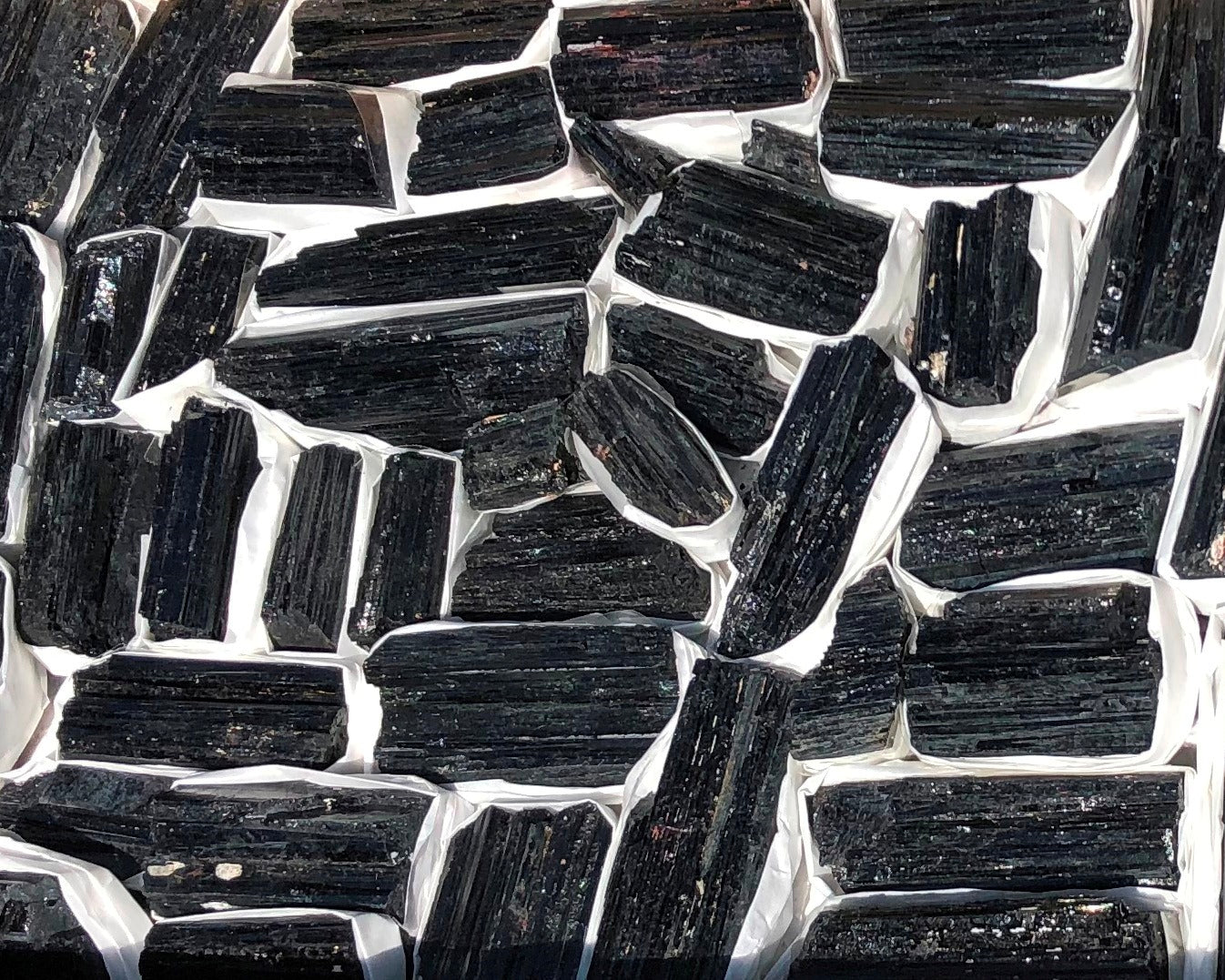 Ansicht von oben: Vielzahl an Turmalin Kristallen auf weißem Hintergrund