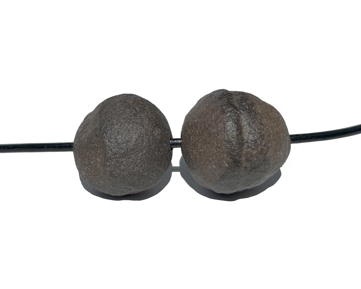 Moqui Marbles mit Band paarweise nebeneinander auf weißem Hintergrund