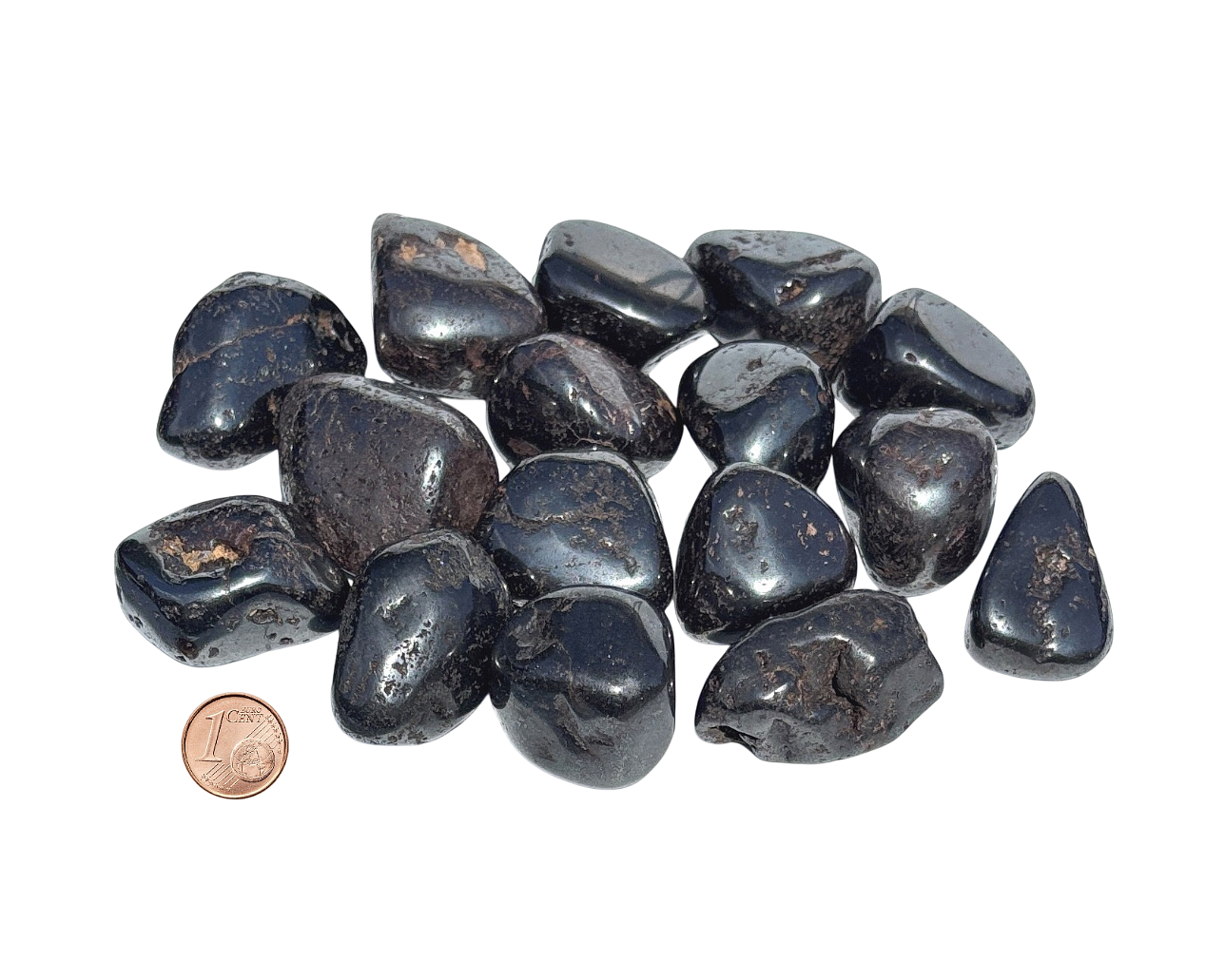 Vielzahl an Magnetit Trommelsteine mit Pfennig Größenvergleich auf weißem Hintergrund
