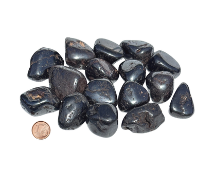 Vielzahl an Magnetit Trommelsteine mit Pfennig Größenvergleich auf weißem Hintergrund