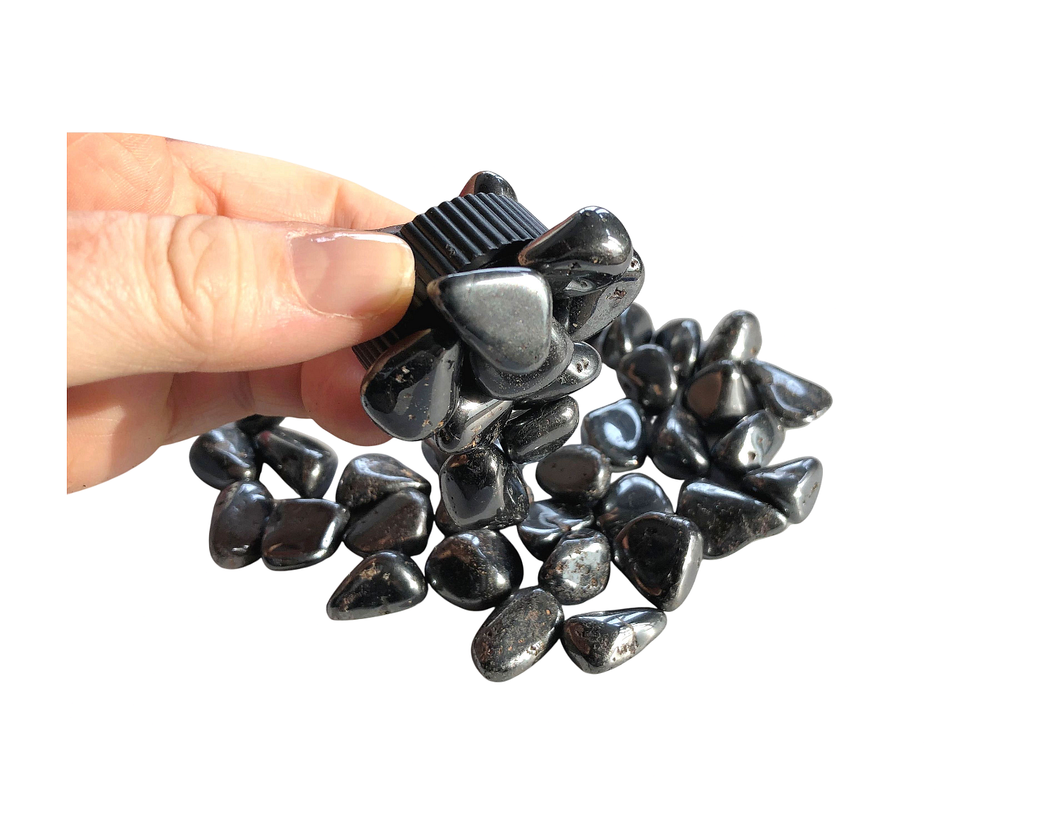 Magnetit Trommelsteine mit Magnet in der Hand auf weißem Hintergrund