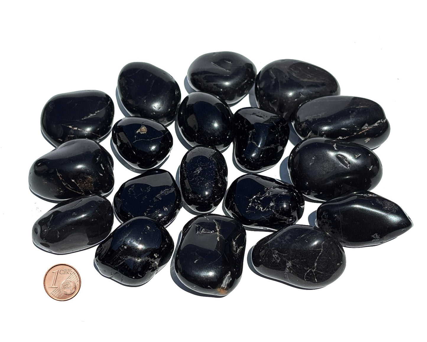 Vielzahl an Turmalin Trommelsteinen auf weißem Hintergrund Größenvergleich mit einem Pfennig