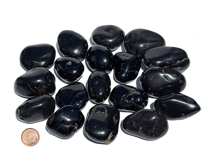 Vielzahl an Turmalin Trommelsteinen auf weißem Hintergrund Größenvergleich mit einem Pfennig