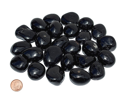 Vielzahl an Turmalin Trommelsteinen auf weißem Hintergrund Größenvergleich mit einem Pfennig