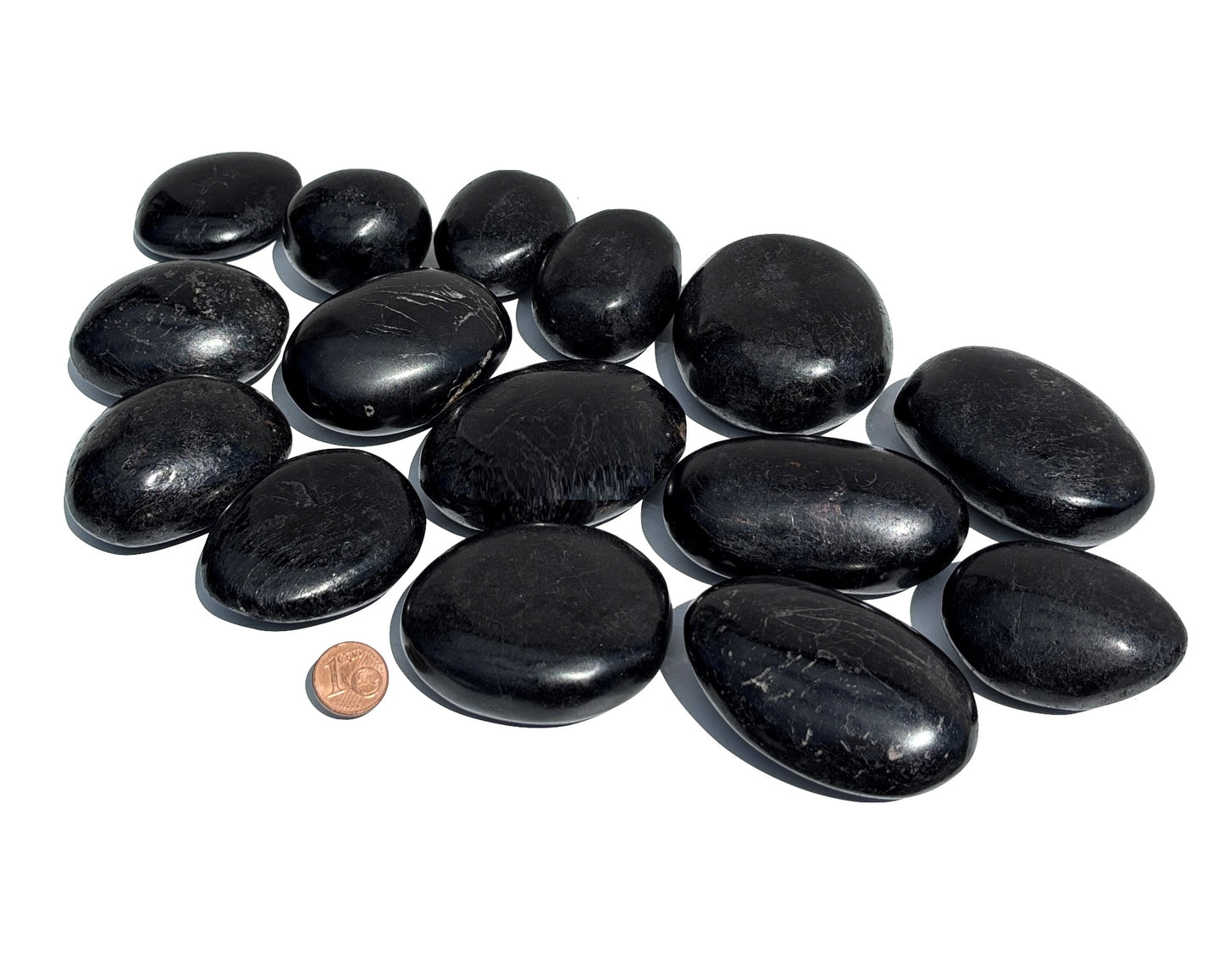 Vielzahl an Turmalin Trommelsteinen auf weißem Hintergrund Größenvergleich mit einem Pfennig