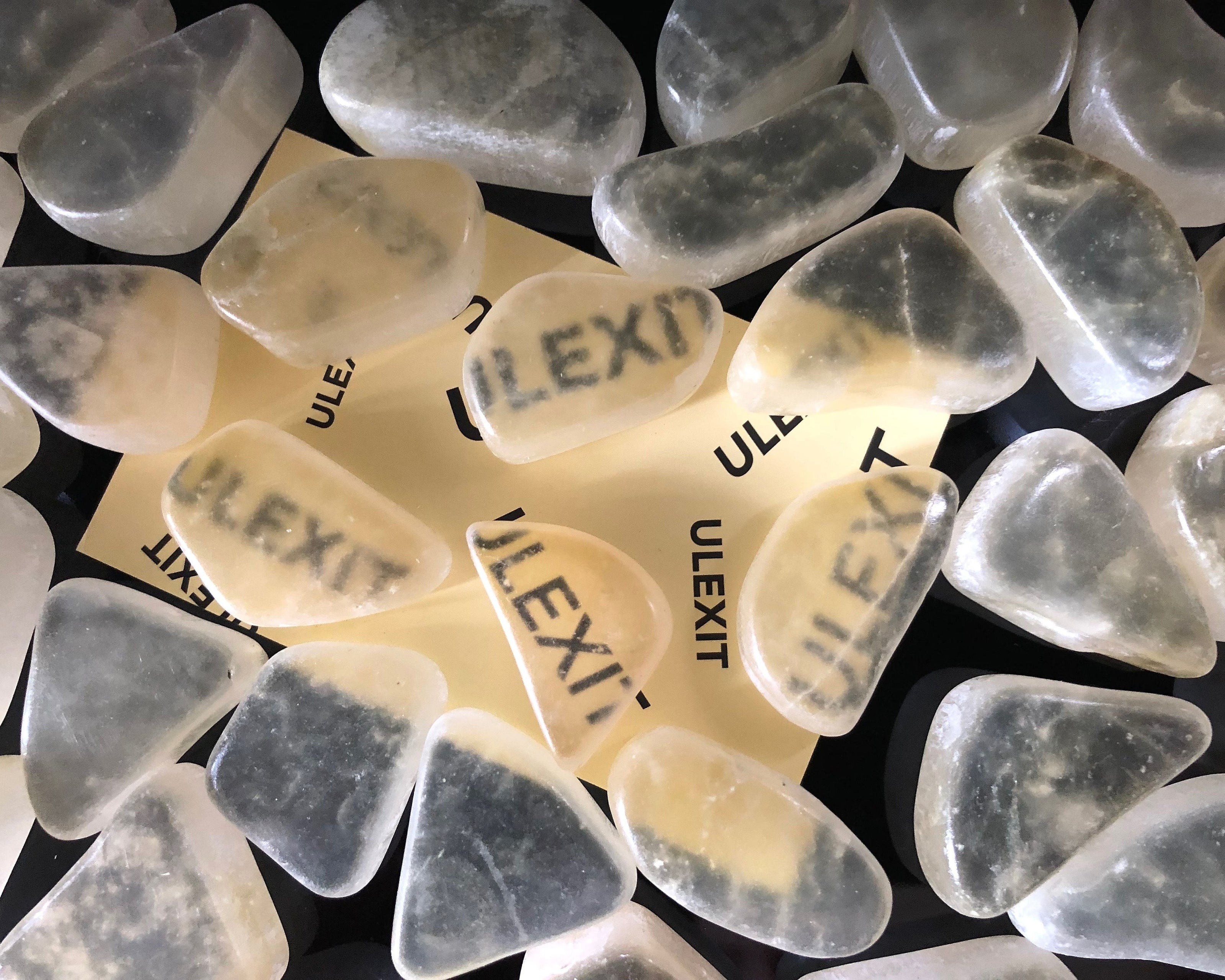 Ansicht von oben: Ulexit Kristalle mit sichtbaren Schriftzügen auf schwarzem Hintergrund