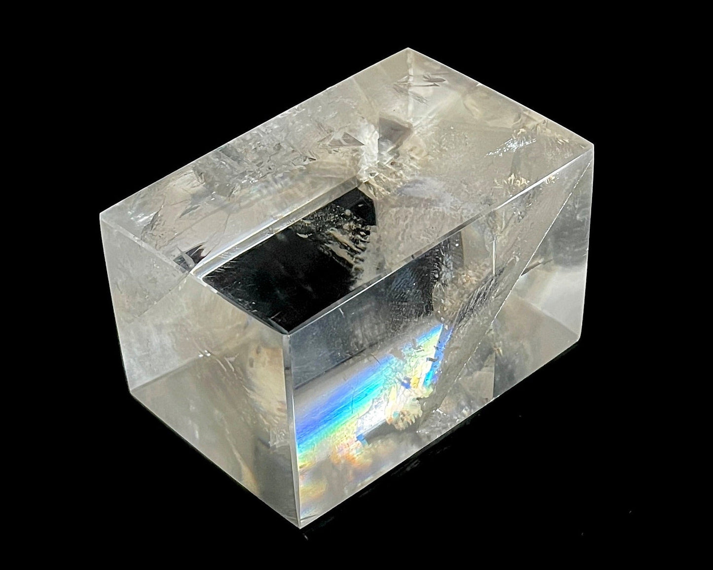 Einzelner polierter Calcit Kristall mit Lichtbrechung auf schwarzem Hintergrund