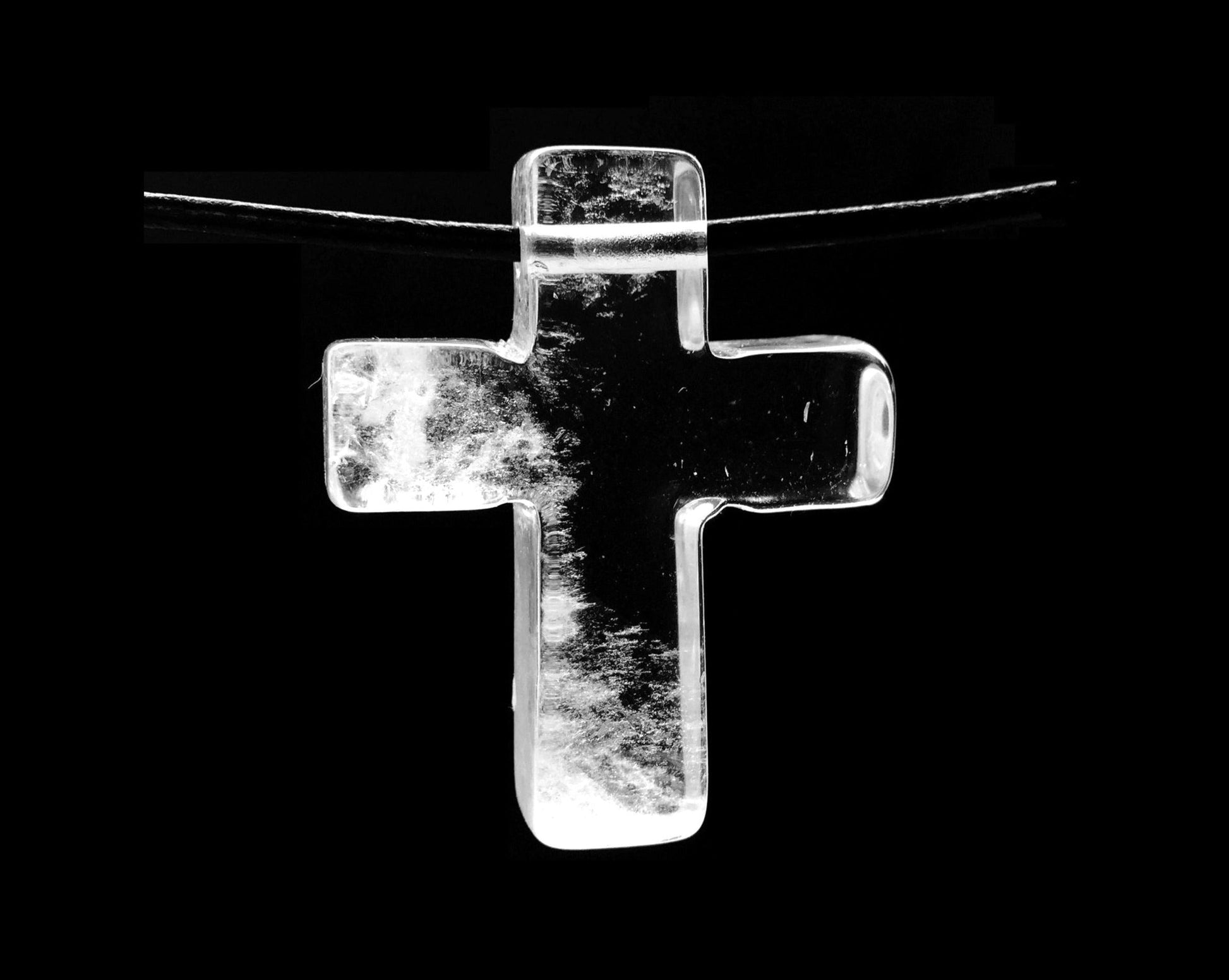 Bergkristall Kreuz als Anhänger auf schwarzem Hintergrund